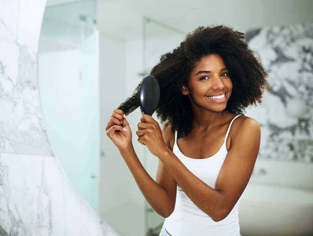 Lady wuth natural hair using a sealant to style her hair