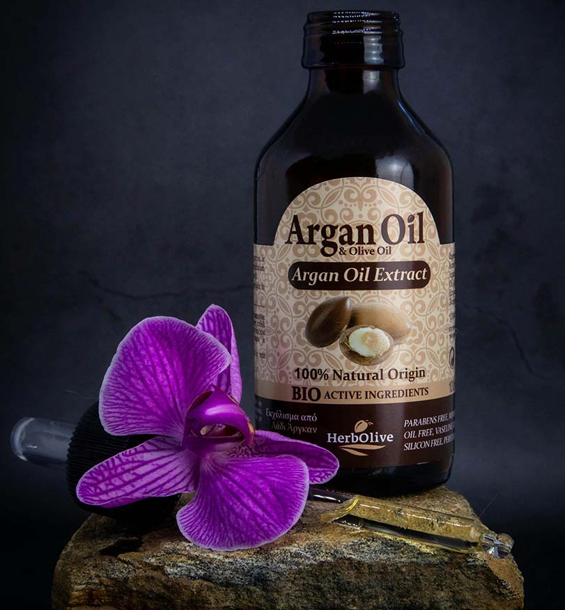 Argan oil in a bottle next to a flower