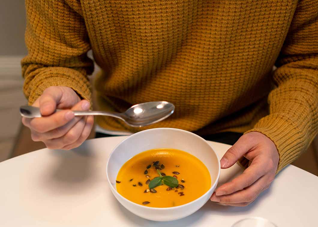 Carrot & lentil soup in a bowl, with a spoon above it
