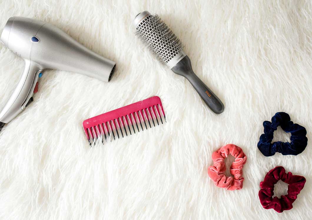 Hair dryer, brush and hair ties for natural hair on a table