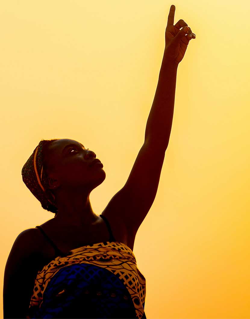 Girl with afro-textured hair pointing at the sun