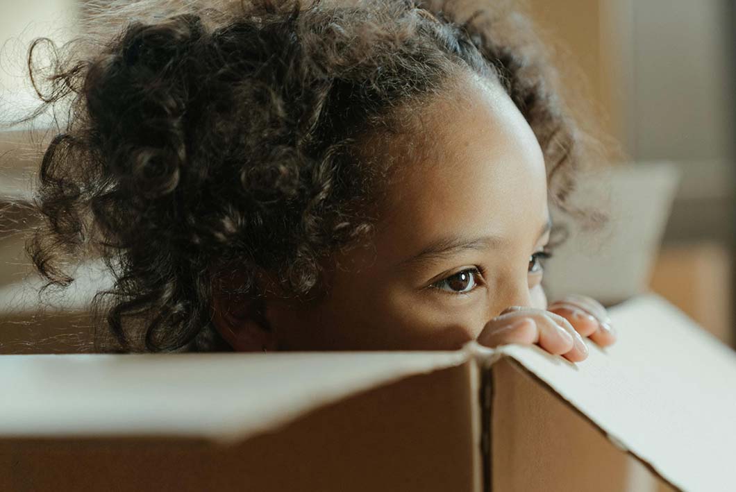 Little girl with natural hair peeking over a box