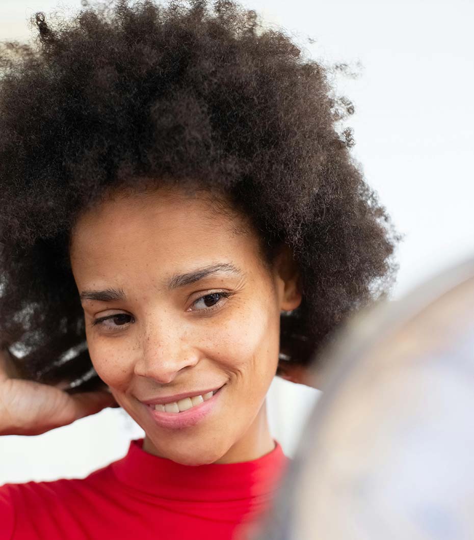 Woman with afro-textured hair looking in the mirror