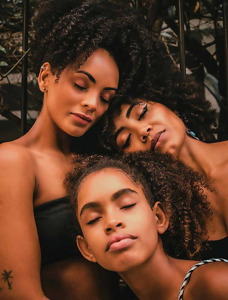 Three ladies with natural hair their afro-textured hairstyles and how to care for afro-textured hair using the lOC or LCO method.