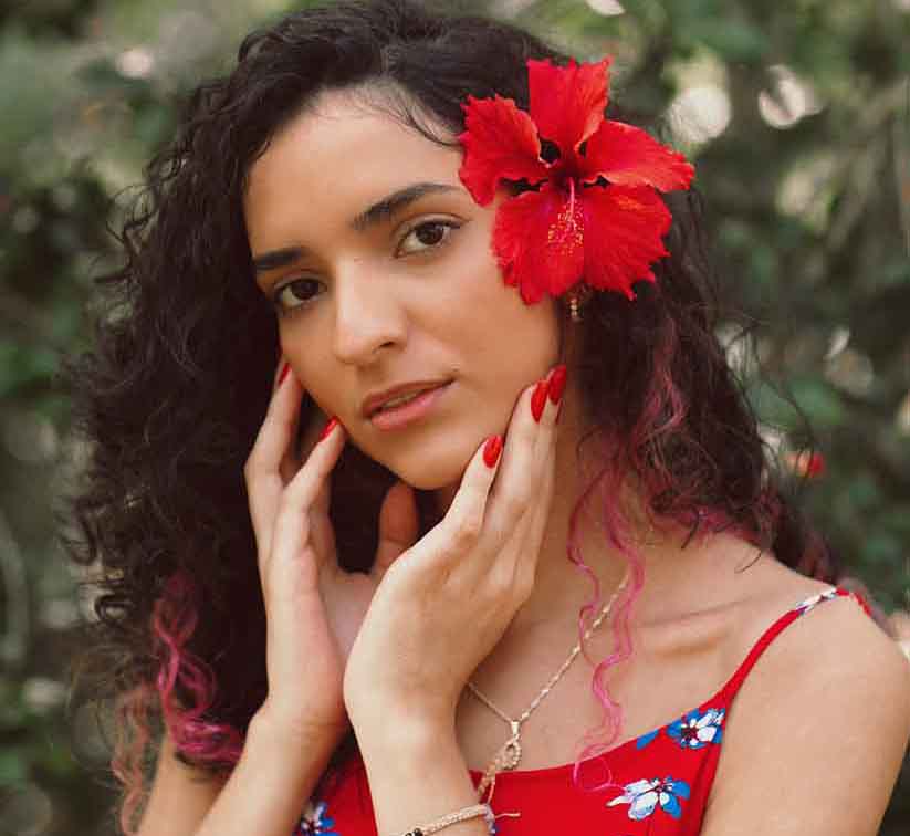 Woman with natural hair wears hibiscus flower on her head