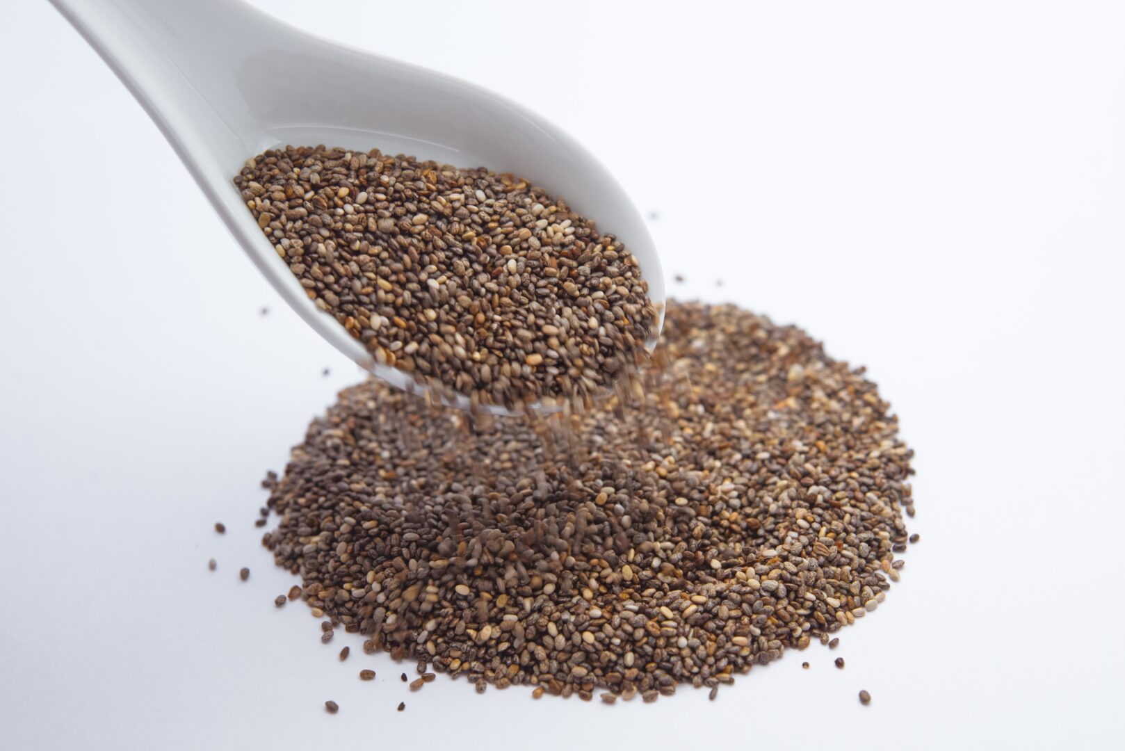 Chia seeds being poured from a spoon onto a counter showing how DIY gel can be made from these seeds.