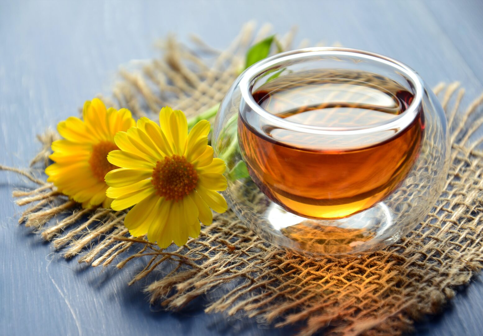 A cup of clove water with some sunflowers around it.