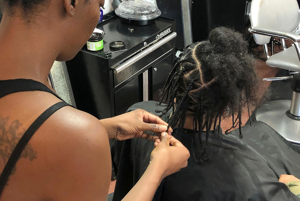 woman braiding natural hair in Jinja