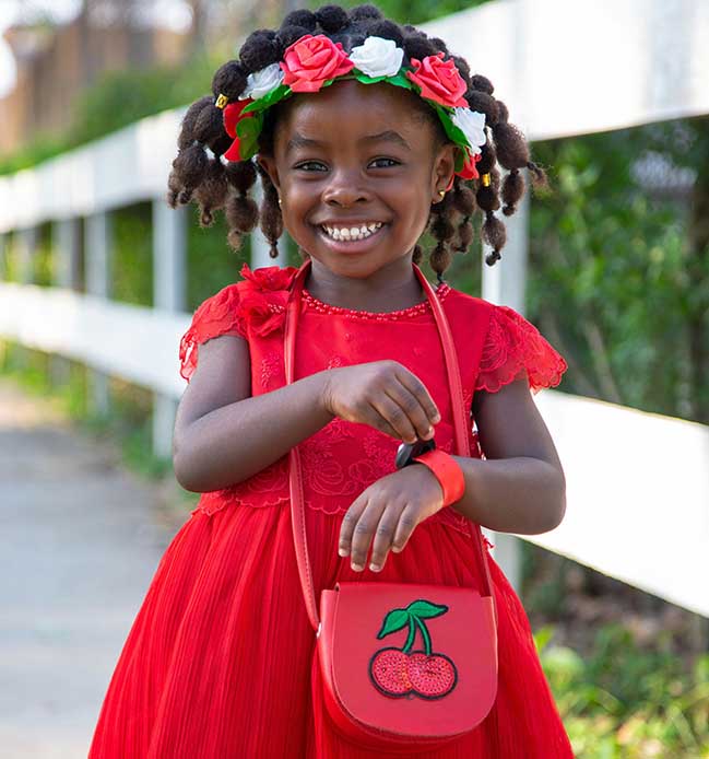 Toddler with cute red dress and hairstyled to show a simple regime for hair care