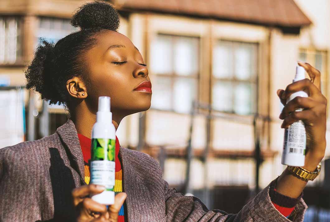 Woman with natural hair holding hair products to detangle natural hair