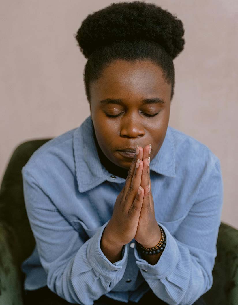 Woman holding her hands in praying posture as she does her daily affirmations for healing
